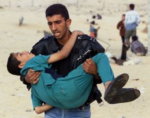 Παλαιστίνιος διαδηλωτής προσπαθεί να απομακρύνει τραυματισμένο παιδί από τα ισραηλινά πυρά...