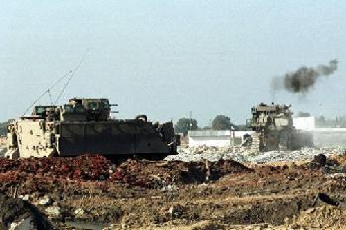 η μπουλντόζα γκρεμίζει ένα Παλαιστινιακό οίκημα υπο την επίβλεψη ενός ισραηλινού στρατιωτικού οχήματος