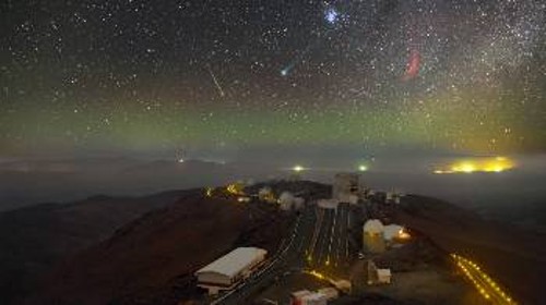 Ο πράσινος κομήτης Λάβτζοϊ (στο κέντρο) περνάει κοντά από τις Πλειάδες (κέντρο προς τα πάνω) και μακριά από το κόκκινο νεφέλωμα Καλιφόρνια, σε αυτή τη φωτογραφία του ουρανού πάνω από το Λα Σίλα της Χιλής. Στο κέντρο δεξιά, ο παναμερικανικός αυτοκινητόδρομος κάνει ξεκάθαρη την παρουσία του...