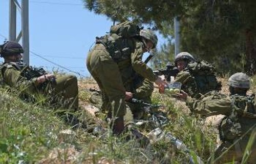 Ισραηλινοί στρατιώτες παίρνουν το σύντομο γεύμα τους, όσο οι μπουλντόζες γκρεμίζουν ένα σπίτι εκεί κοντά...