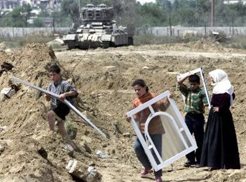 Ο,τι μπορούν να σώσουν από το γκρεμισμένο σπίτι τους υπό το «βλέμμα» του ισραηλινού τανκ στη Ράφα