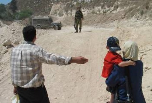 Παλαιστίνιος δείχνει τη γυναίκα και το παιδί του από μακριά στον ισραηλινό στρατιώτη για να περάσει τη γραμμή αποκλεισμού