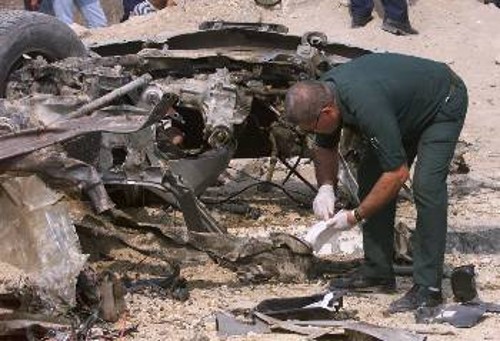 Παλαιστίνιος αστυνομικός εξετάζει τα υπολείμματα του αυτοκινήτου μετά την έκρηξη