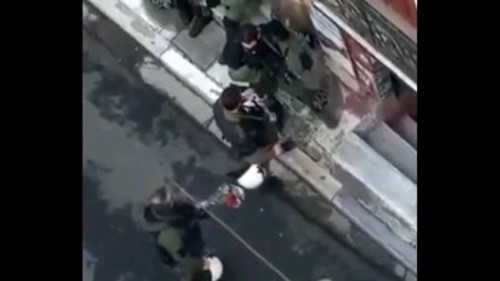 Εικόνα από το ερασιτεχνικό βίντεο που δείχνει τον αστυνομικό να δυαλυεί την ανθοδέσμη στην πλάτη συναδέλφου του στα Εξάρχεια
